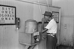 Negro drinking at "Colored" water cooler in streetcar terminal, Oklahoma City, Oklahoma by Russell Lee.jpg